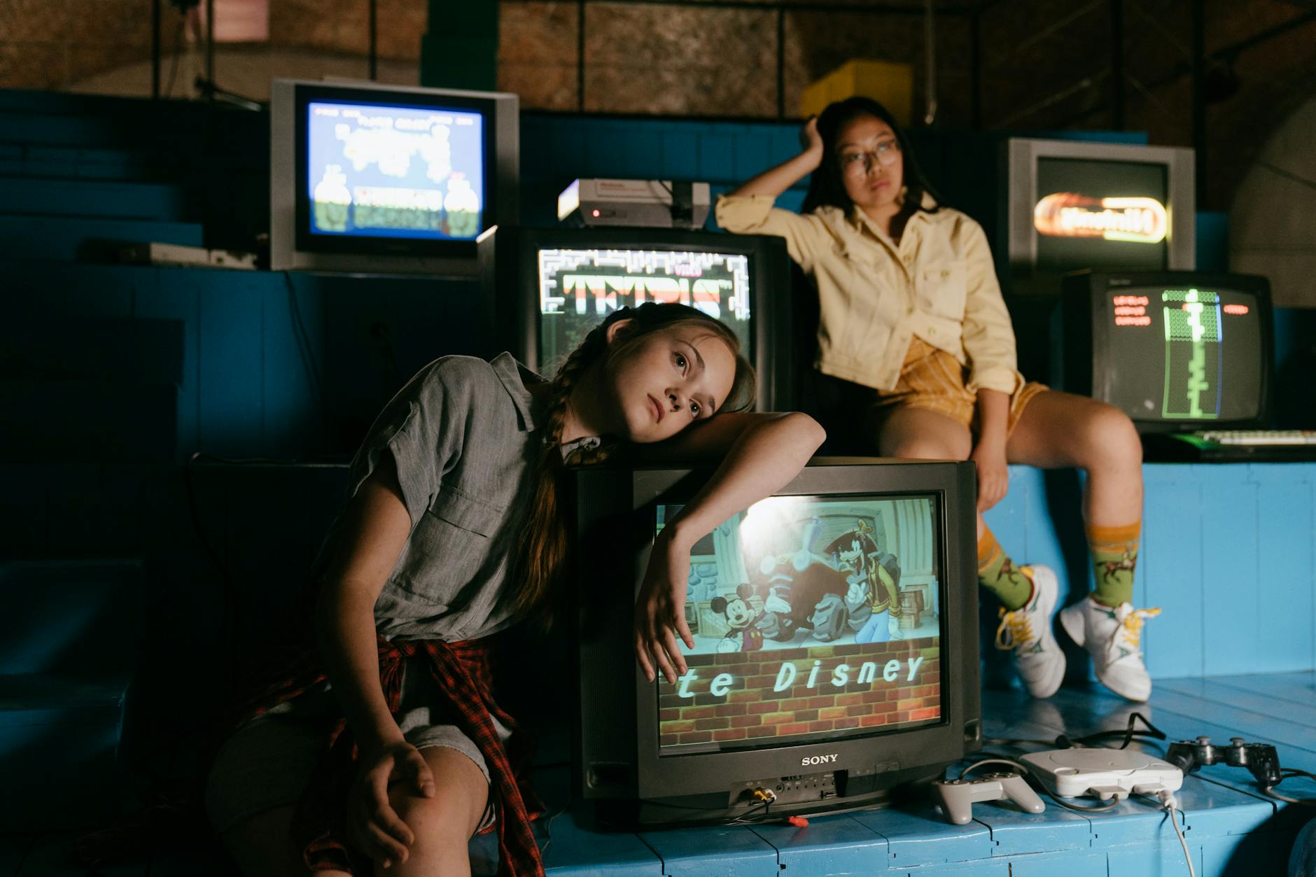 girls leaning on television units